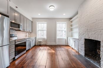 a kitchen with a large brick fireplace and hardwood floors